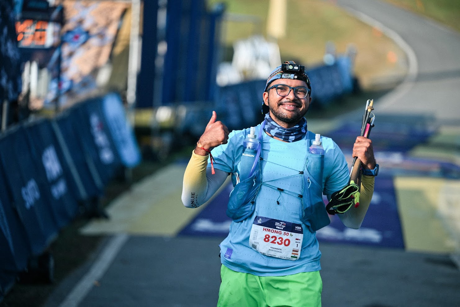 Prashanth Vaidya at the UTMB Chiangmai 56K finish line with trekking poles, hydration vest, and headlamp